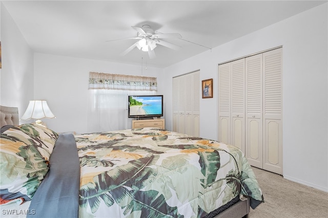 bedroom featuring ceiling fan, light carpet, and two closets