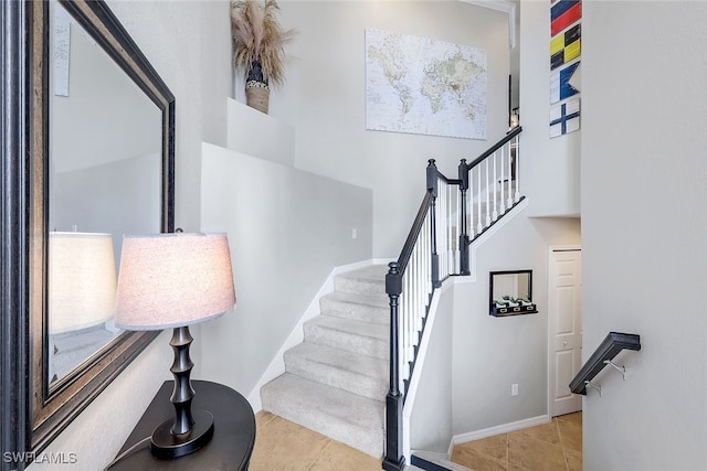 staircase with tile patterned floors and a high ceiling