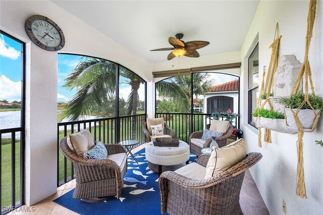 sunroom featuring a water view and ceiling fan