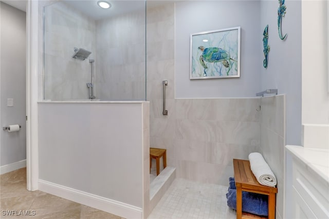 bathroom featuring a tile shower, vanity, and tile patterned flooring