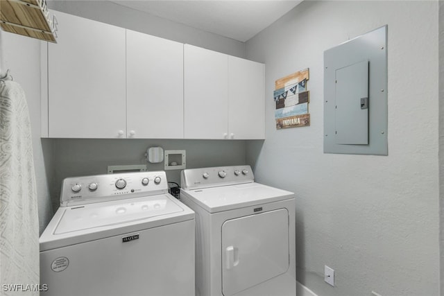 laundry room featuring electric panel, washer and clothes dryer, and cabinets