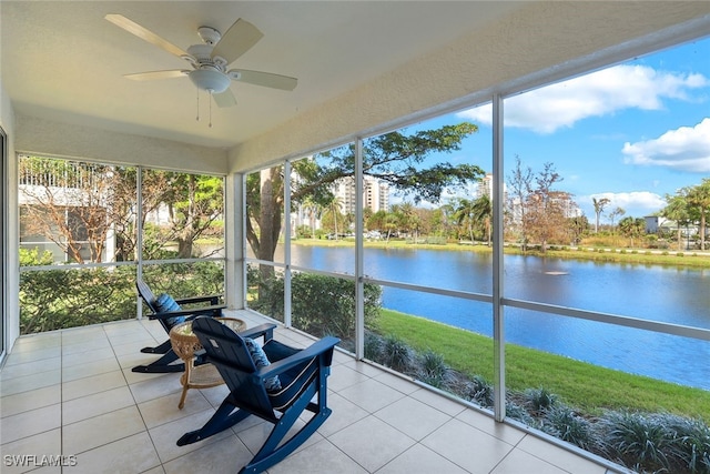 sunroom / solarium with ceiling fan and a water view