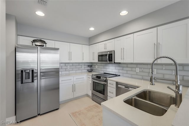 kitchen featuring sink, appliances with stainless steel finishes, tasteful backsplash, light tile patterned flooring, and white cabinetry