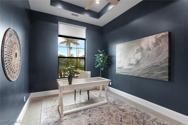 office with carpet, ceiling fan, and a tray ceiling