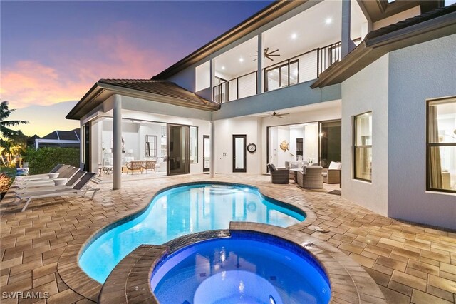 pool at dusk featuring an in ground hot tub, an outdoor hangout area, ceiling fan, and a patio area