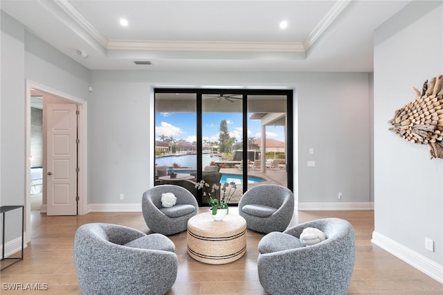 living area featuring ornamental molding, light hardwood / wood-style flooring, and a tray ceiling