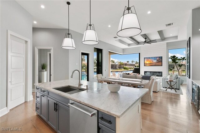 kitchen with gray cabinets, sink, hanging light fixtures, and a center island with sink