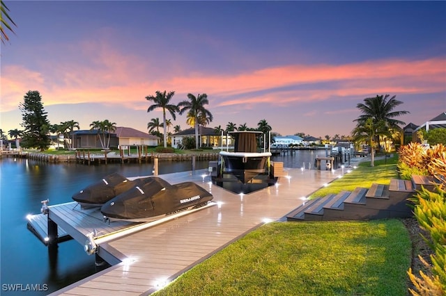 view of dock with a lawn and a water view