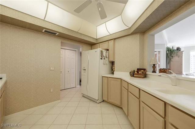 kitchen featuring ceiling fan, white fridge with ice dispenser, sink, crown molding, and light brown cabinetry