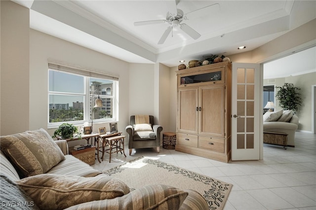 living area with ceiling fan, light tile patterned floors, crown molding, and a tray ceiling