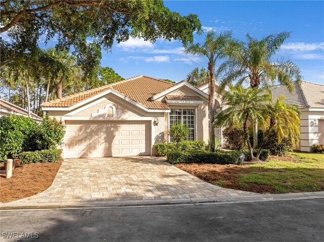 view of front of property with a tiled roof, an attached garage, driveway, and stucco siding