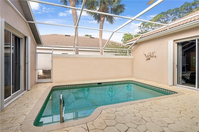 view of pool with glass enclosure and a patio