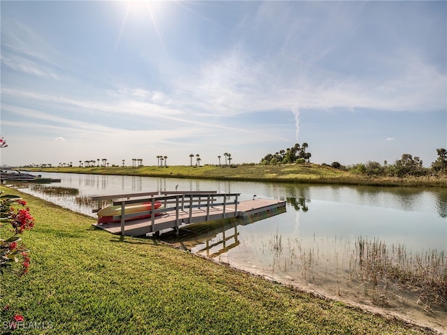 view of dock with a water view and a lawn