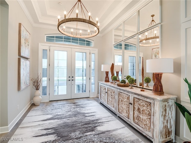 doorway with french doors, a tray ceiling, hardwood / wood-style floors, crown molding, and an inviting chandelier