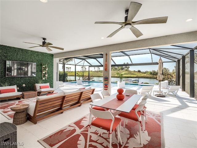 view of patio with a water view, ceiling fan, a lanai, and an outdoor living space