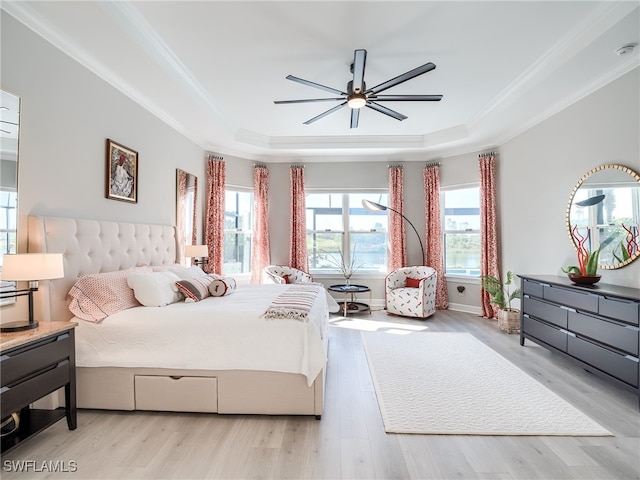 bedroom with light hardwood / wood-style floors, a raised ceiling, ornamental molding, and ceiling fan