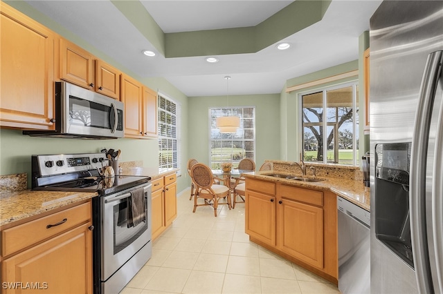 kitchen with sink, appliances with stainless steel finishes, light stone counters, and a raised ceiling