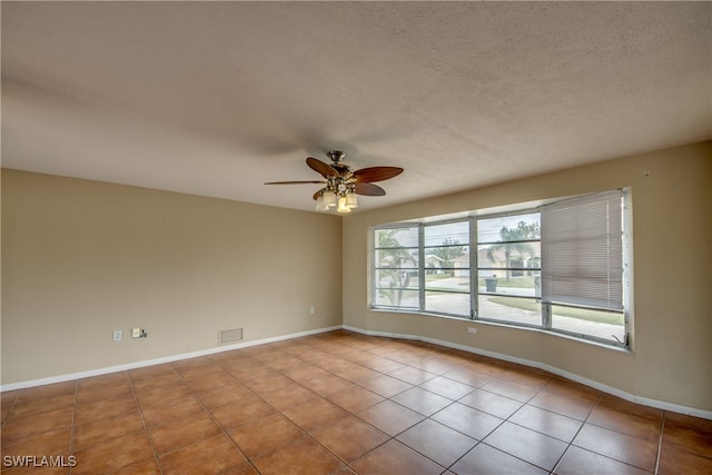 tiled spare room featuring a textured ceiling and ceiling fan