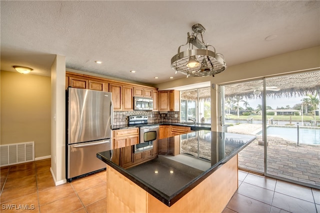 kitchen featuring appliances with stainless steel finishes, decorative backsplash, a center island, and light tile patterned floors