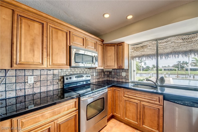 kitchen featuring tasteful backsplash, a textured ceiling, light tile patterned flooring, sink, and stainless steel appliances