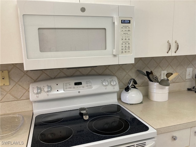 kitchen with white appliances, white cabinetry, light countertops, and decorative backsplash