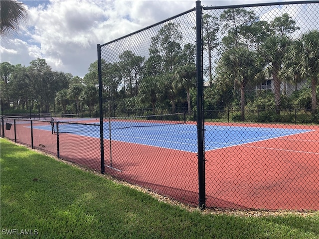 view of tennis court with fence and a lawn