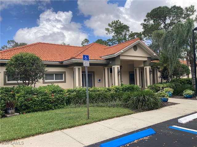 view of front of home with a front lawn, a tile roof, and stucco siding