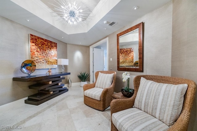 sitting room featuring an inviting chandelier and a tray ceiling