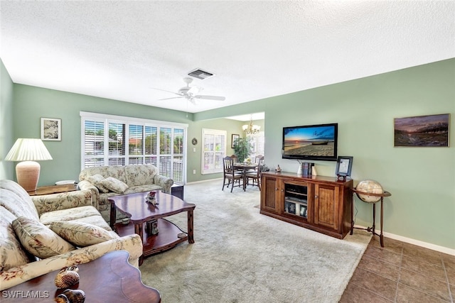 tiled living room with a textured ceiling and ceiling fan with notable chandelier