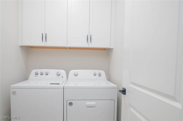 clothes washing area featuring cabinets and separate washer and dryer