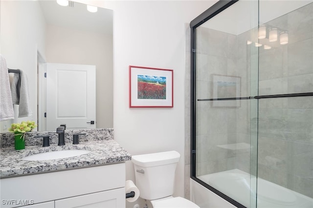 full bathroom featuring vanity, combined bath / shower with glass door, and toilet