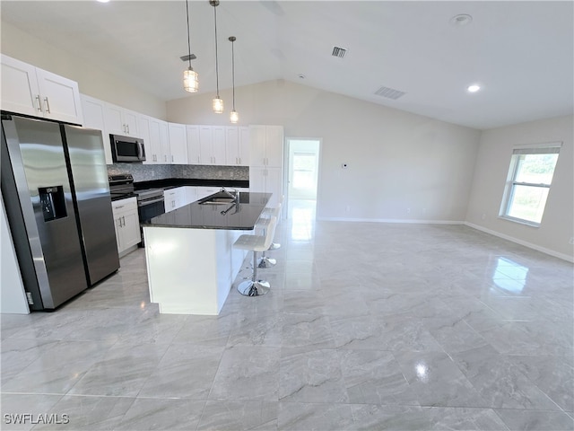 kitchen with appliances with stainless steel finishes, sink, decorative light fixtures, white cabinetry, and lofted ceiling