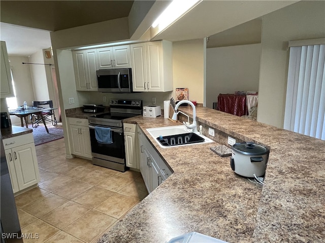 kitchen with sink, white cabinets, stainless steel appliances, and light tile patterned flooring