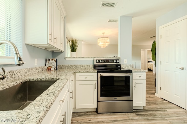 kitchen with sink, stainless steel electric range oven, light stone counters, and white cabinetry