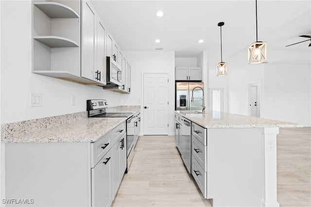833 Newell St E, Lehigh Acres, FL 33974 - kitchen with stainless steel appliances, open shelves, light wood finished floors, an island with sink, and recessed lighting