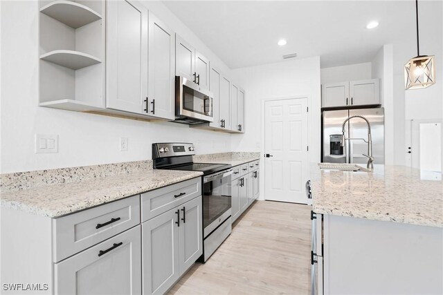 833 Newell St E, Lehigh Acres, FL 33974 - kitchen with stainless steel appliances, open shelves, recessed lighting, light wood-style flooring, and light stone counters