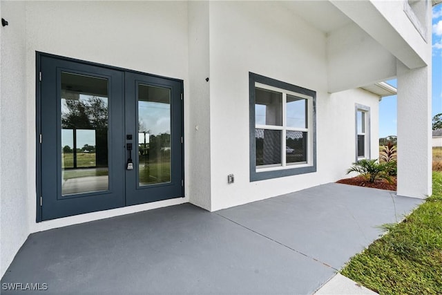 833 Newell St E, Lehigh Acres, FL 33974 - view of exterior entry featuring french doors, stucco siding, and a patio area