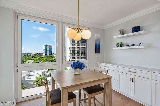 dining room with light hardwood / wood-style floors, an inviting chandelier, and crown molding