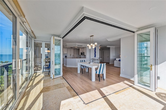 interior space with a notable chandelier, french doors, a wealth of natural light, and light hardwood / wood-style flooring