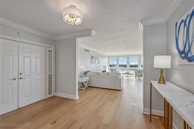 foyer entrance featuring crown molding and light wood-type flooring