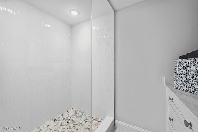 bathroom featuring a tile shower and vanity