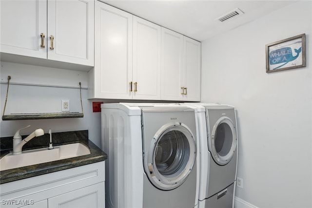 laundry area featuring washing machine and clothes dryer, cabinets, and sink