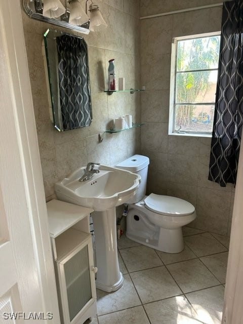 bathroom featuring toilet, tile patterned floors, and tile walls