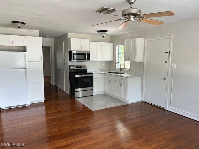 kitchen with dark hardwood / wood-style flooring, appliances with stainless steel finishes, sink, and white cabinets