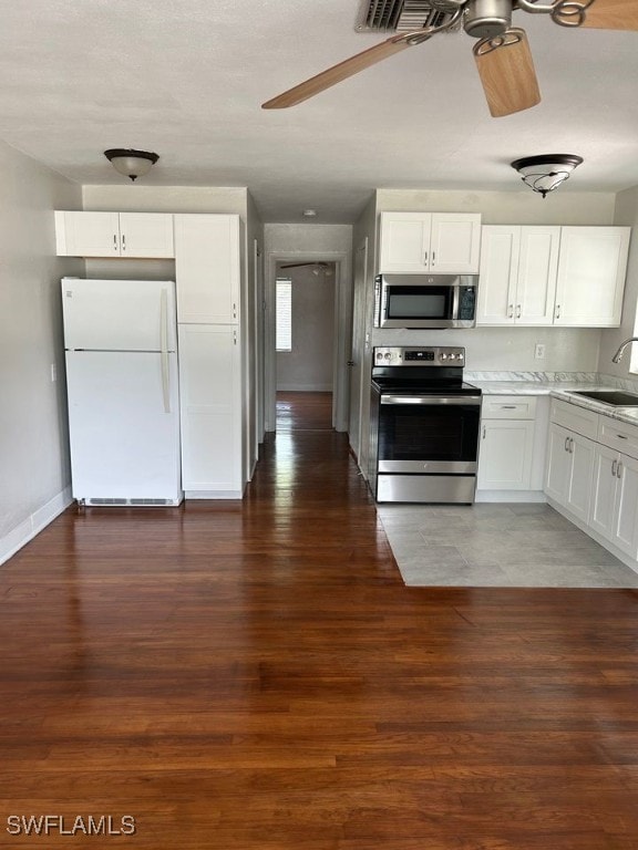 kitchen with dark hardwood / wood-style floors, sink, white cabinetry, appliances with stainless steel finishes, and ceiling fan