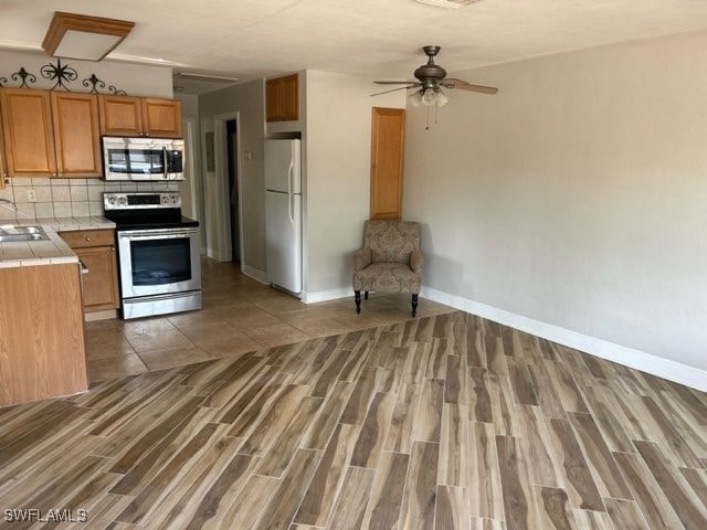 kitchen with appliances with stainless steel finishes, tile countertops, and wood-type flooring