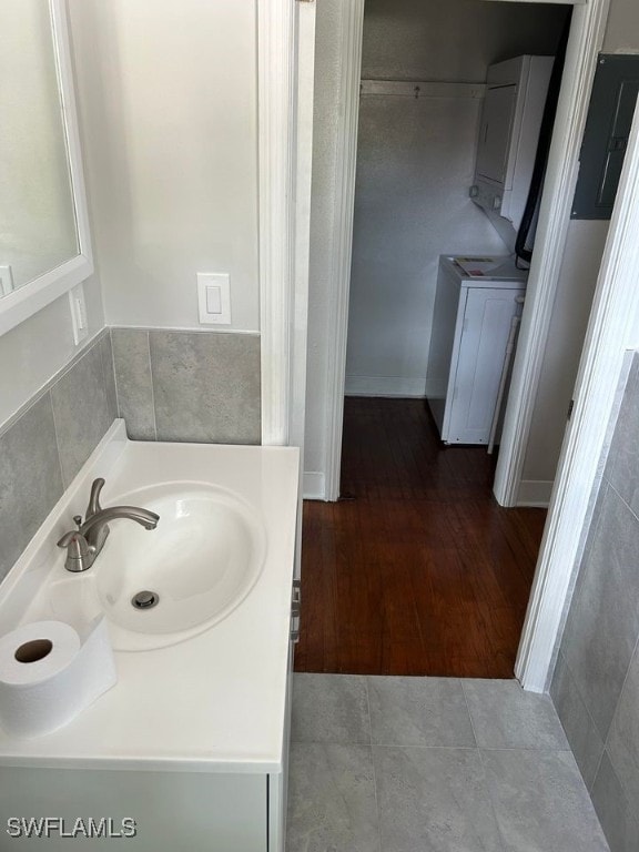 bathroom featuring vanity, hardwood / wood-style flooring, washer / dryer, and electric panel