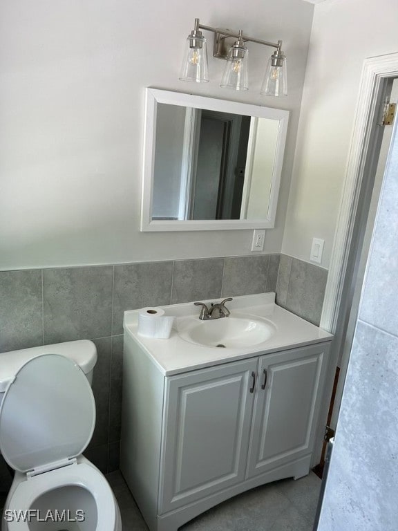 bathroom with tile walls, vanity, and toilet