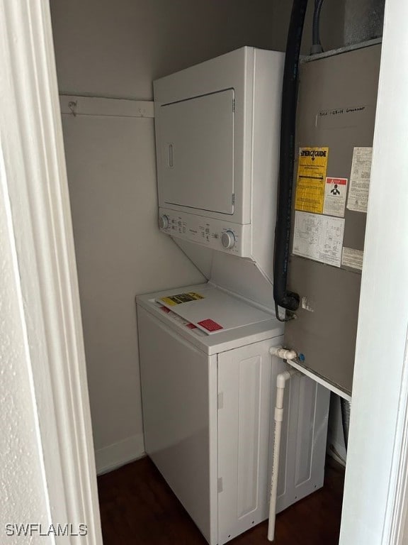 laundry area with dark hardwood / wood-style flooring and stacked washer and clothes dryer