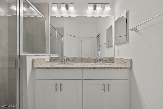 bathroom featuring a shower with door and vanity